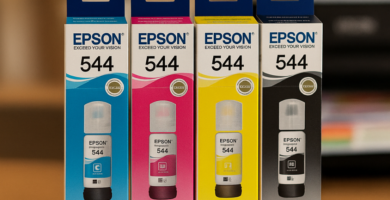 Cuatro botellas de tinta Epson 544 (negra, cian, magenta y amarilla) dispuestas en fila sobre un expositor redondo. En las pancartas se puede leer "Originales" y "Entrega sin recargo". Al fondo, una impresora borrosa.